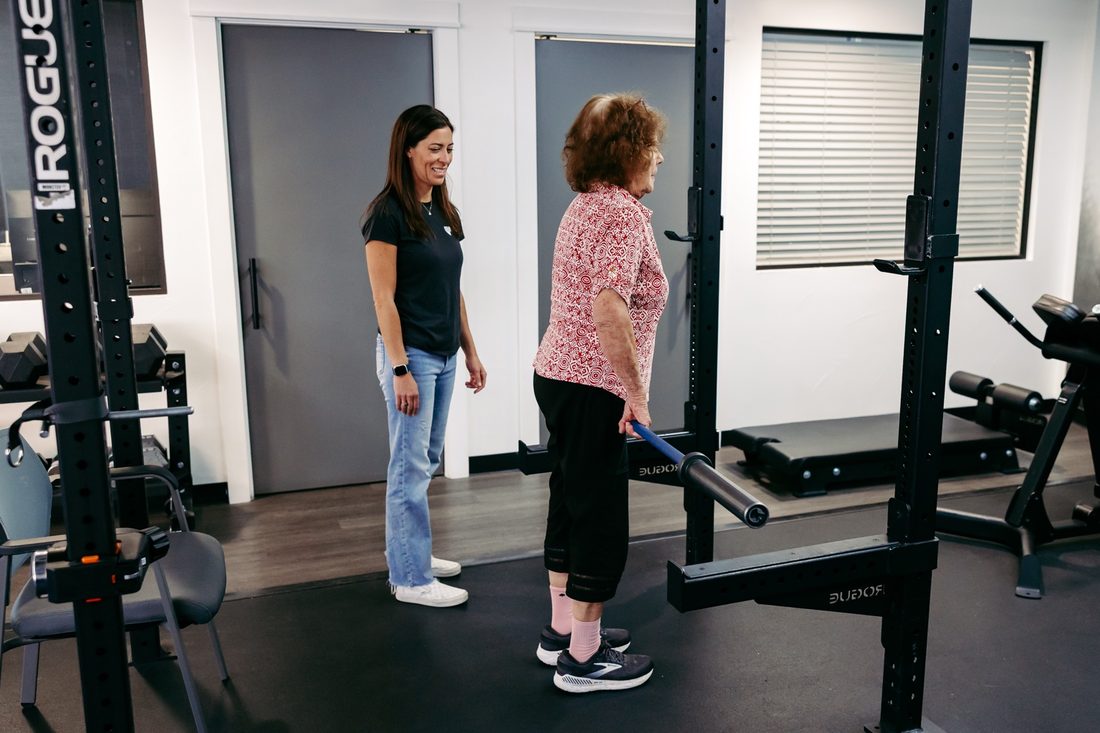 A Nevada Physical Therapy clinician coaching a woman through a barbell lift