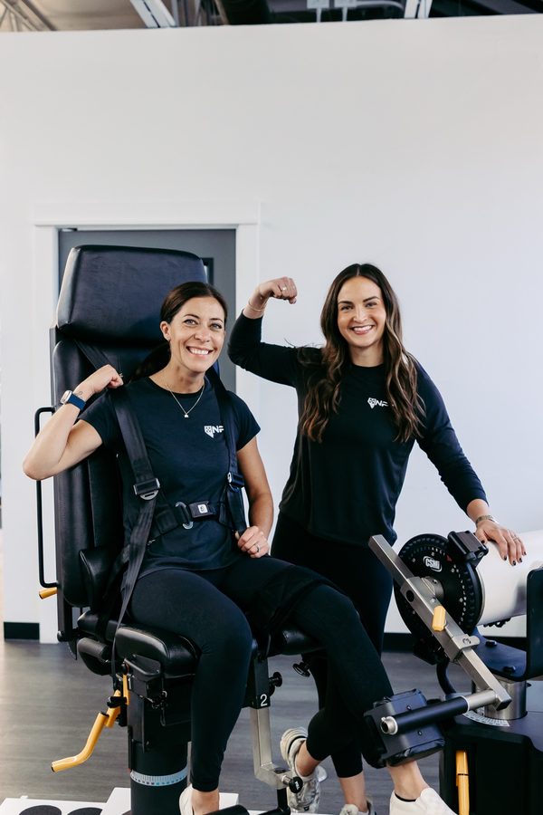 A patient and clinician smiling and flexing after strength testing